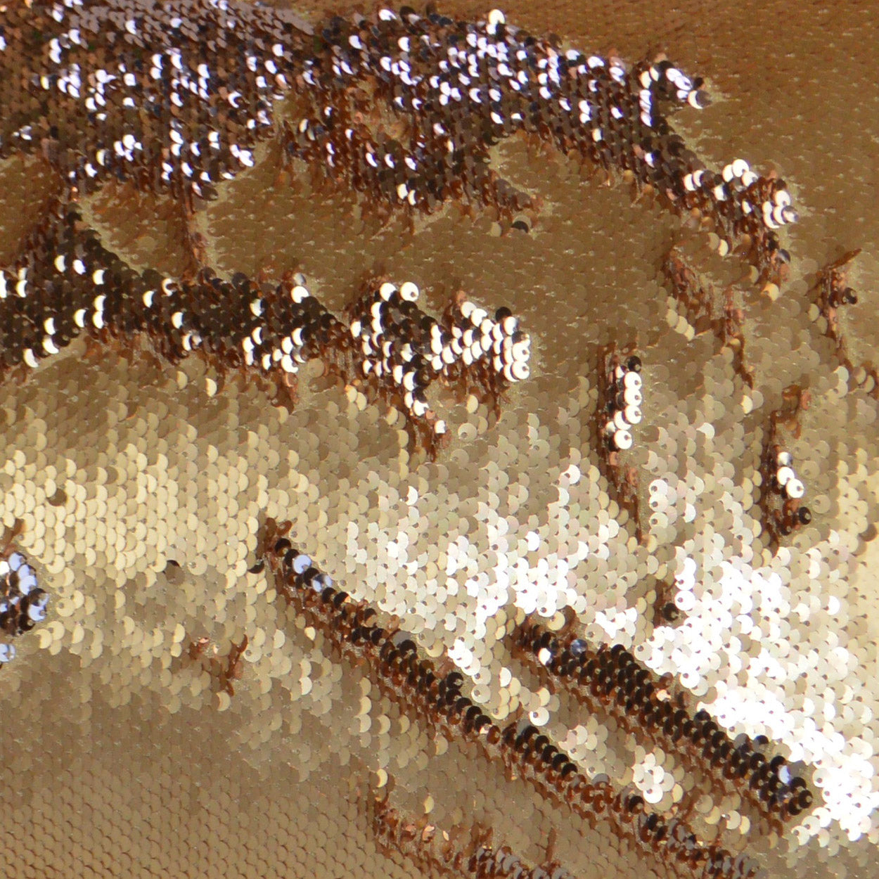Close-up of gold and bronze sequin fabric; shiny metallic sequins create a sparkling, wavy pattern.