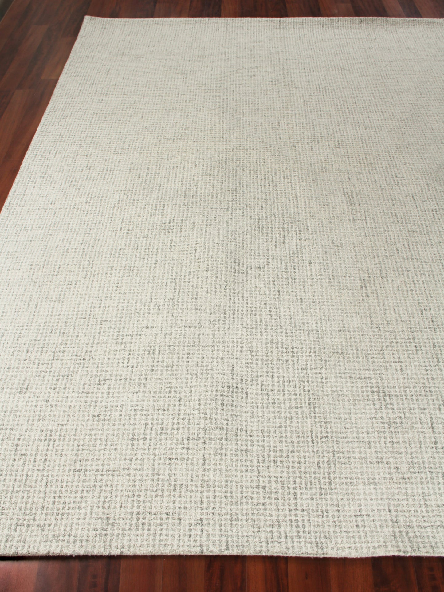 Beige textured rectangular area rug with soft woven pattern on hardwood floor; light pink edge trim.
