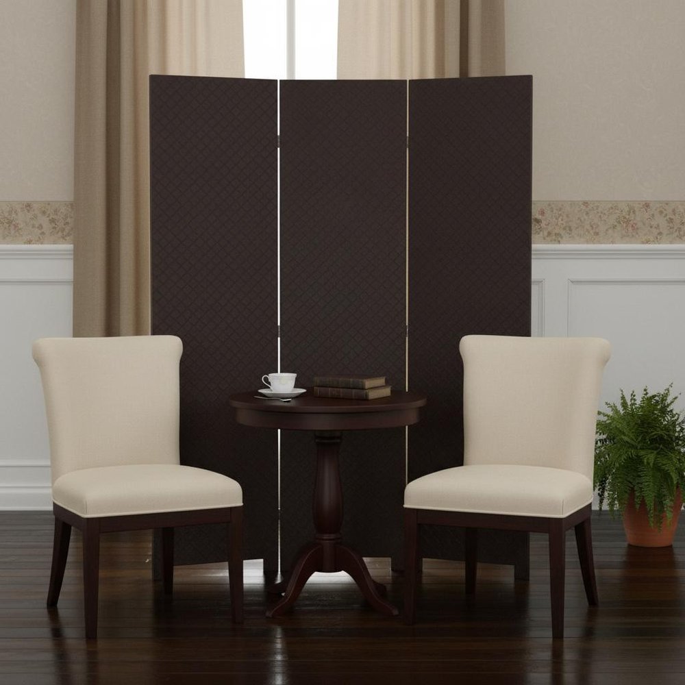 Cream upholstered chairs with dark wood legs flank a round table with a cup and books, in front of a brown folding screen.