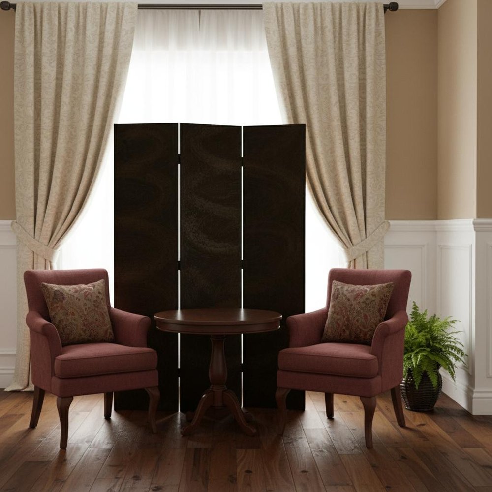 Two burgundy upholstered armchairs flank a round wooden pedestal table; dark folding screen behind, beige drapes and a plant.