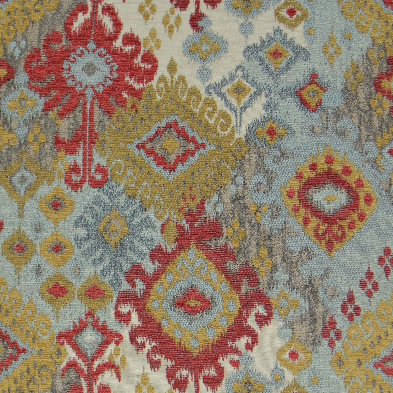 Kilim-style woven fabric with red, gold and blue geometric medallions on cream-gray background.