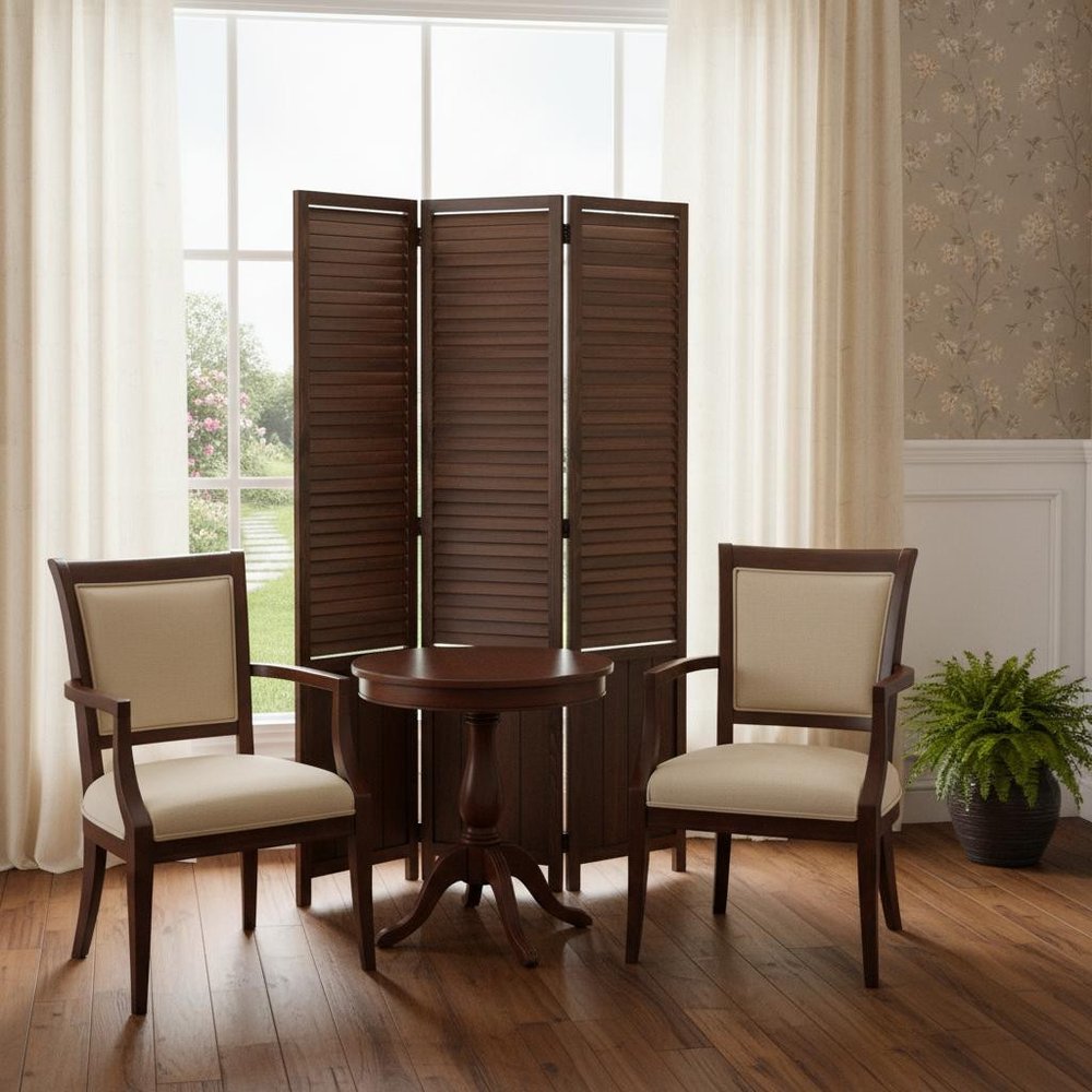 Dark wood round pedestal table with two beige upholstered chairs in a sunlit room & brown folding screen & curtains & plant.