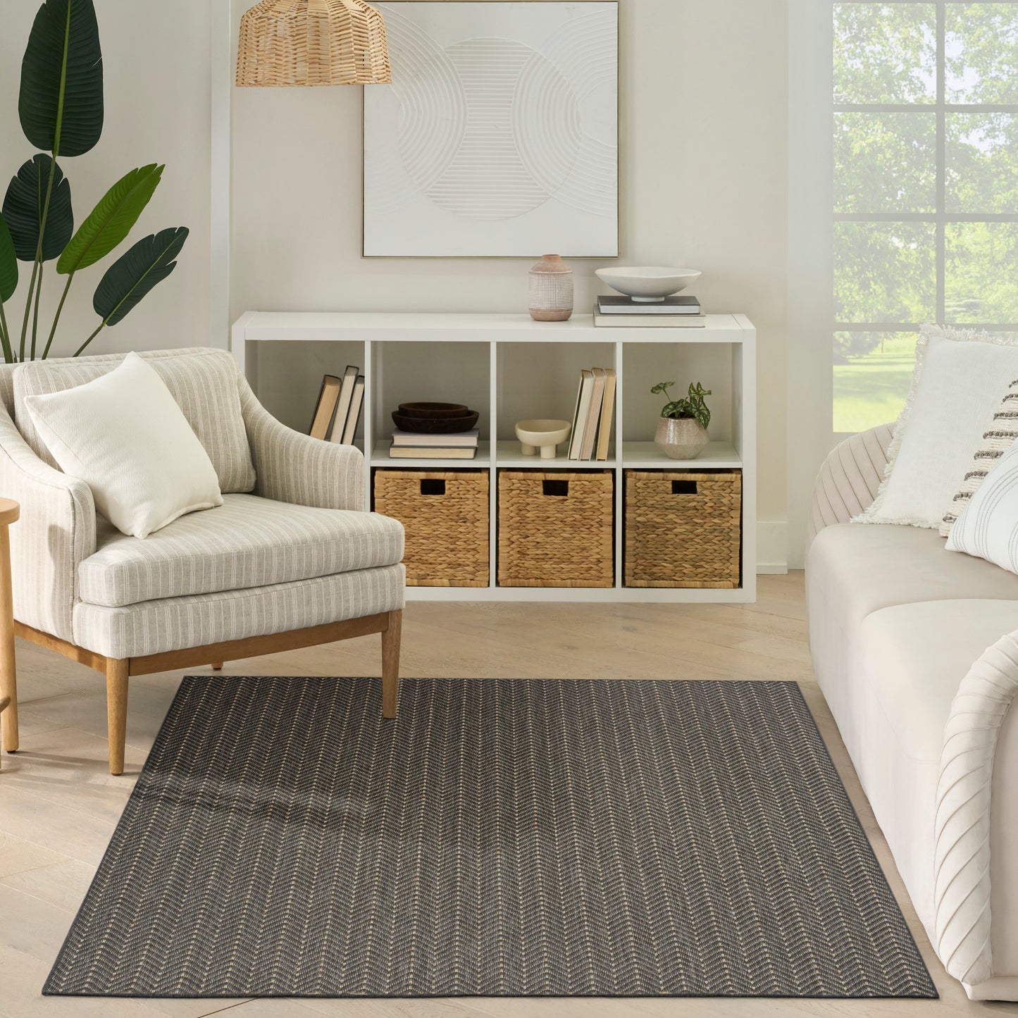 Cozy living room with white console, woven baskets, beige armchair, charcoal patterned rug, and a large window.