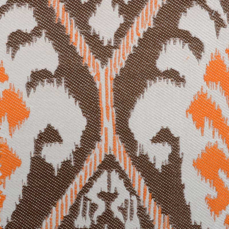 Close-up of woven fabric with orange, brown and cream geometric damask pattern.