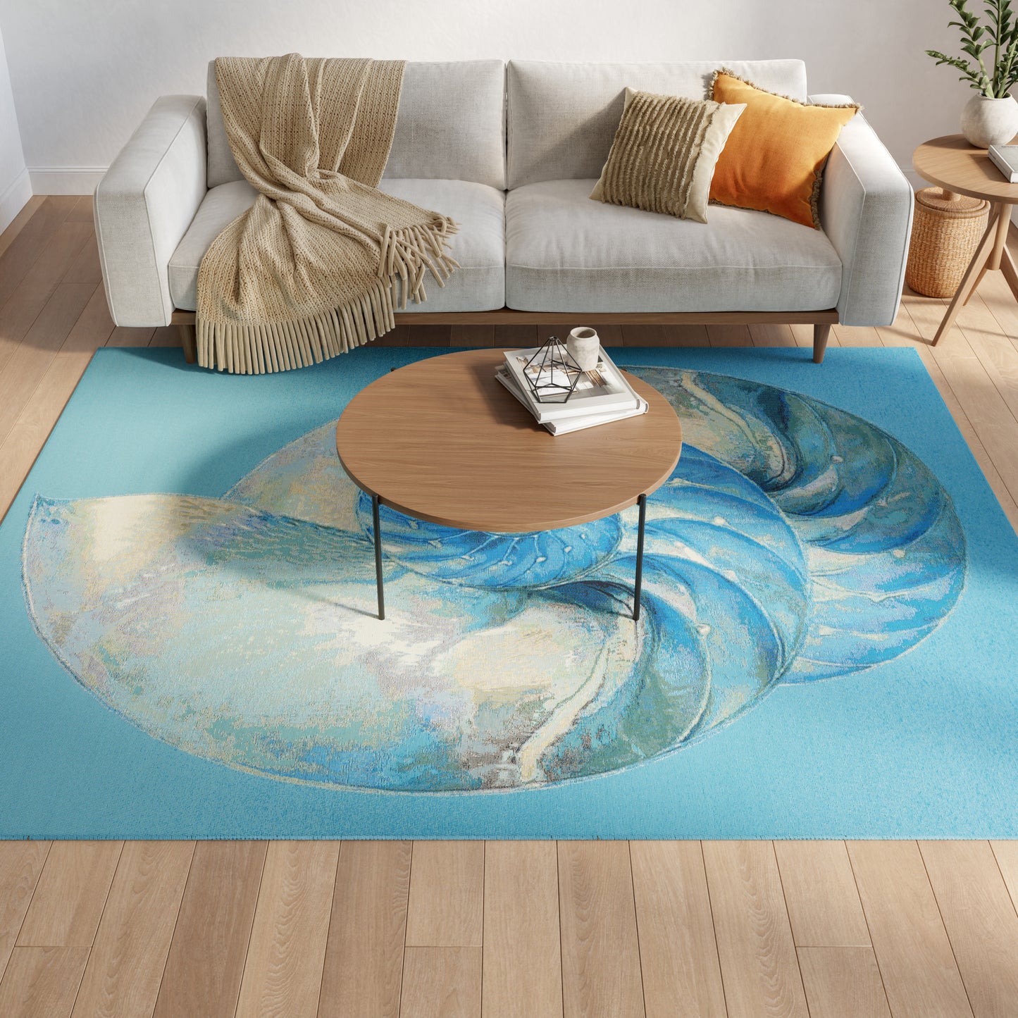 Living room with light gray sofa, beige fringed throw, orange cushion, round wood coffee table, on a turquoise swirl rug.