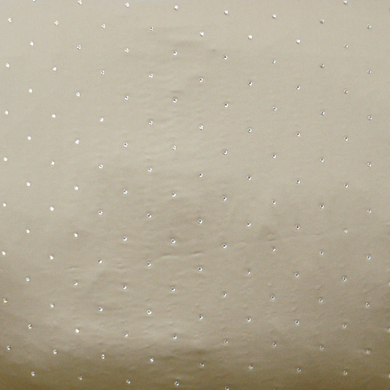 Beige fabric with evenly spaced small white dots; soft, dotted texture for dresses or home decor.
