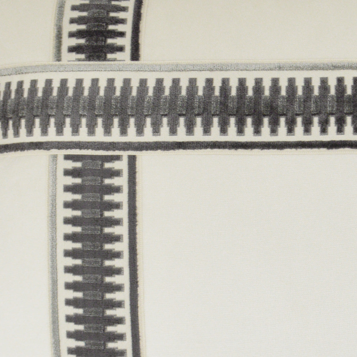 Close-up of black metal zipper teeth on grey fabric of a 24" x 24" pillow, showing cross seam and textured textile detail.