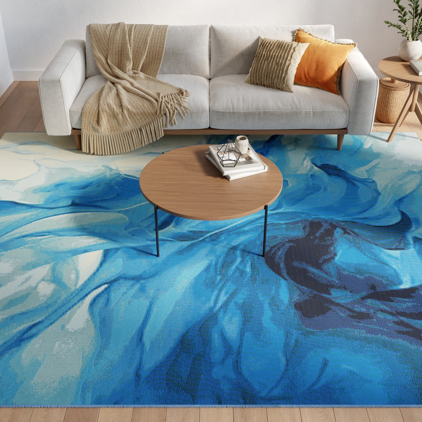 Blue abstract rug in a living room featuring a light gray sofa, beige throw & orange cushion; round wooden coffee table with books.