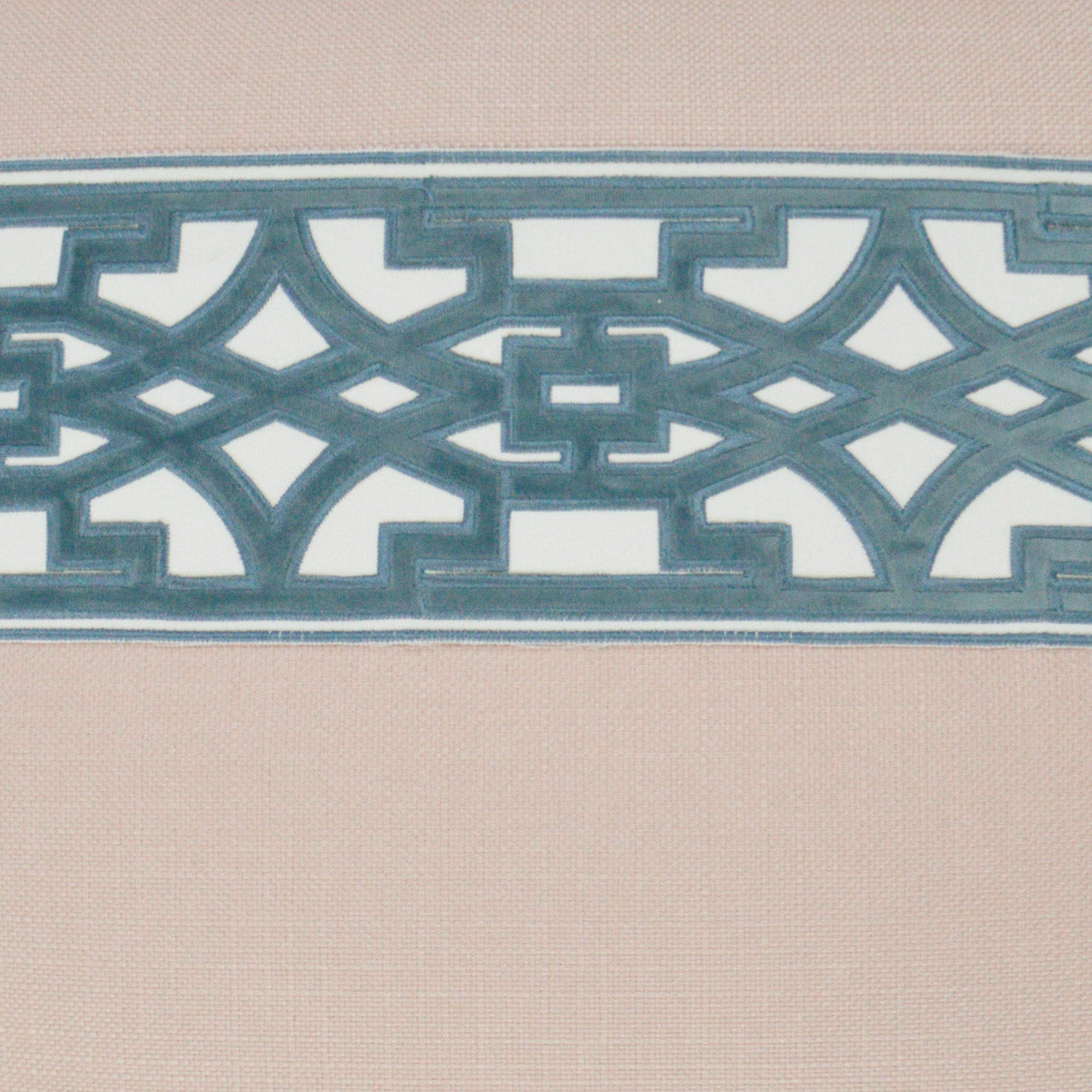 Teal-blue geometric lattice border across beige fabric; decorative interlocking pattern with a modern cutwork look.