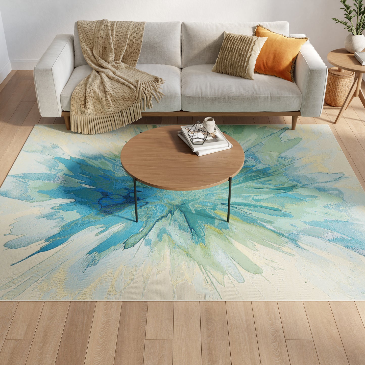 Light gray sofa with beige throw & orange pillow, round wood coffee table on a blue-green watercolor rug.