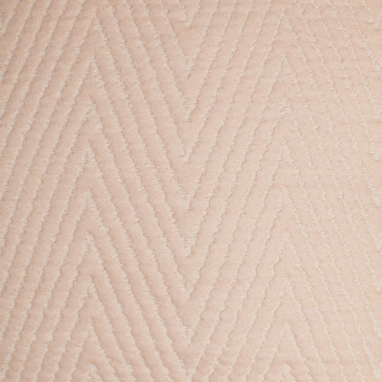 Beige chevron-pattern fabric with raised ridges; soft upholstery or rug material.