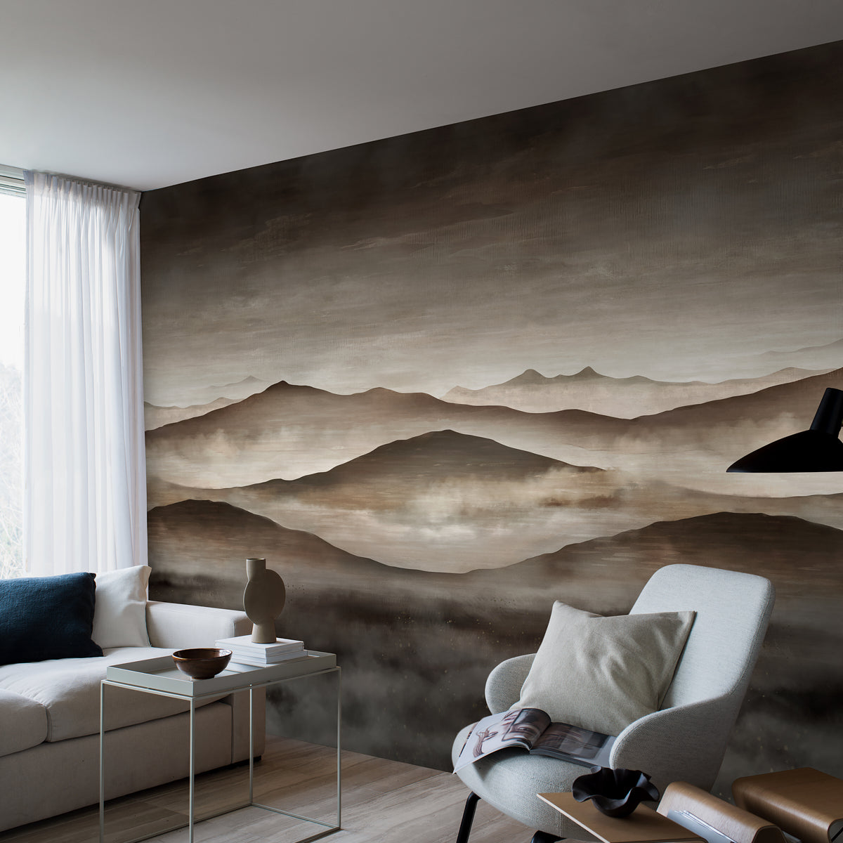Living room with beige sofa, light gray armchair, glass side table, ceramic vase, black floor lamp, brown mountain mural.