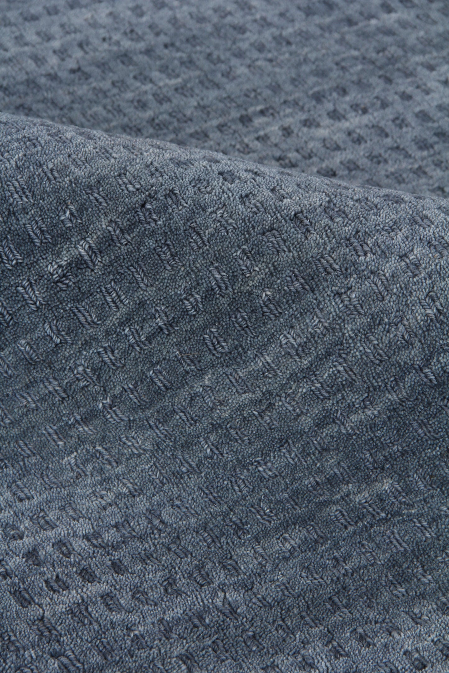 Dark blue rug close-up showing a waffle-knit texture with a small square grid pattern.