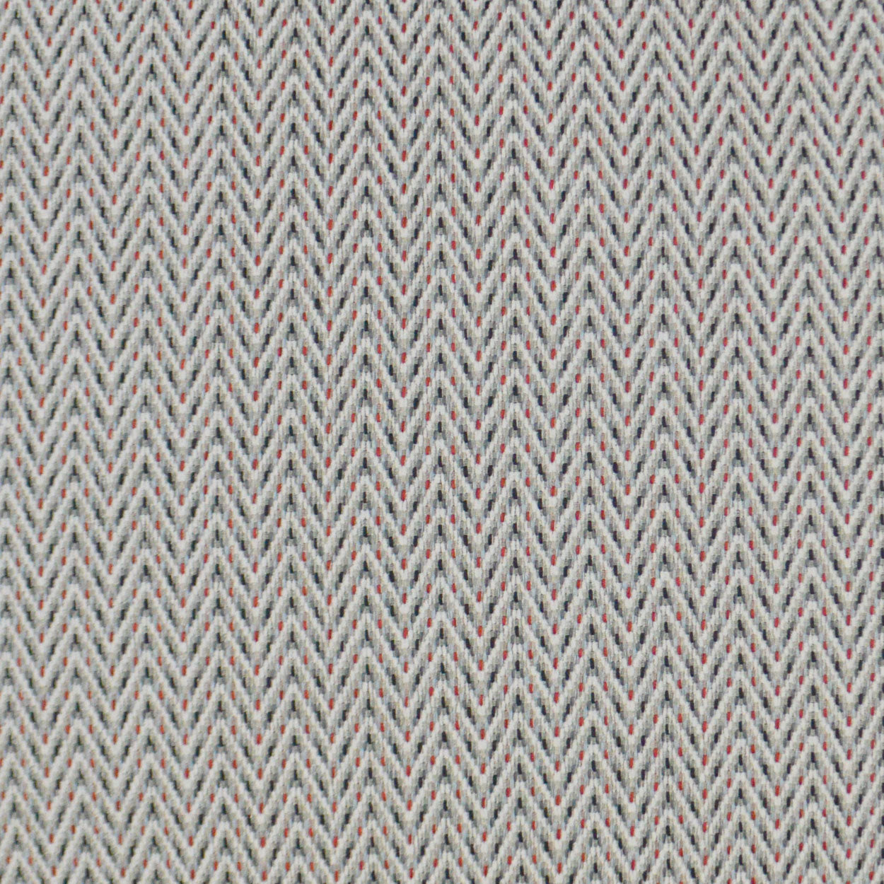 Close-up of herringbone fabric in pale gray with tiny red and blue flecks, woven textile.