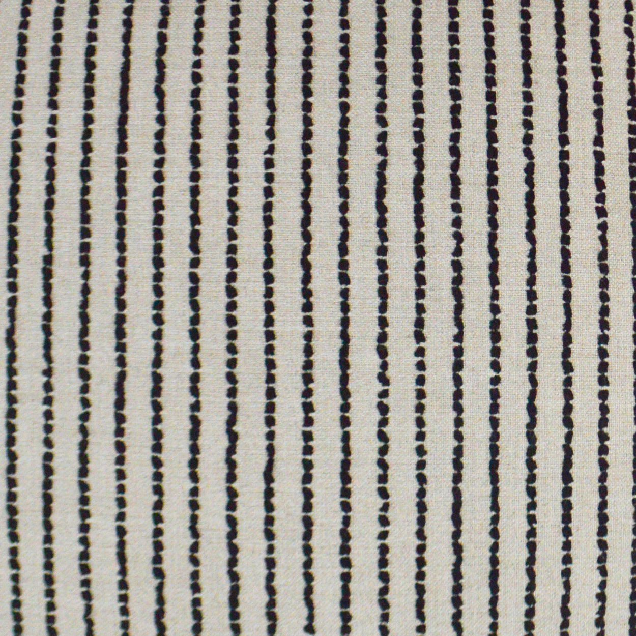 Beige woven fabric with narrow vertical black dotted stripes; versatile upholstery textile.