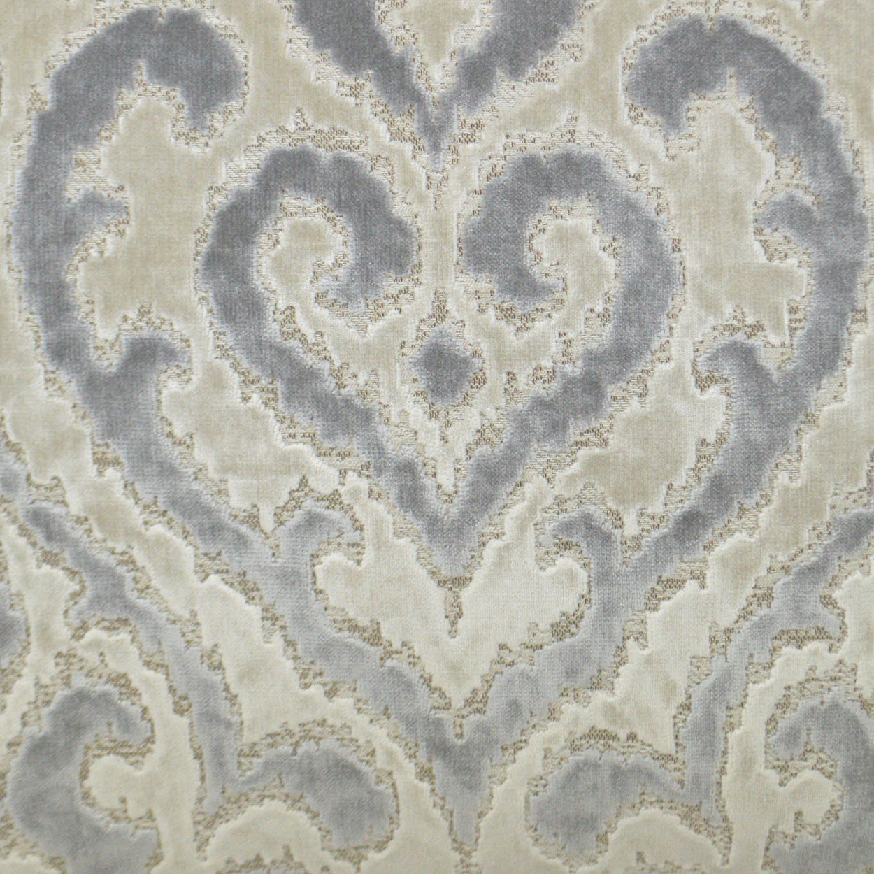 Beige damask-patterned rug in pale blue-gray scroll motif with plush texture.