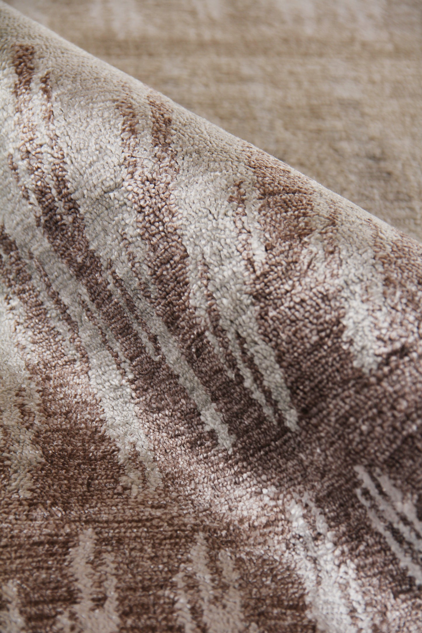Close-up of a plush beige and brown patterned rug with textured pile and abstract stripe motif.
