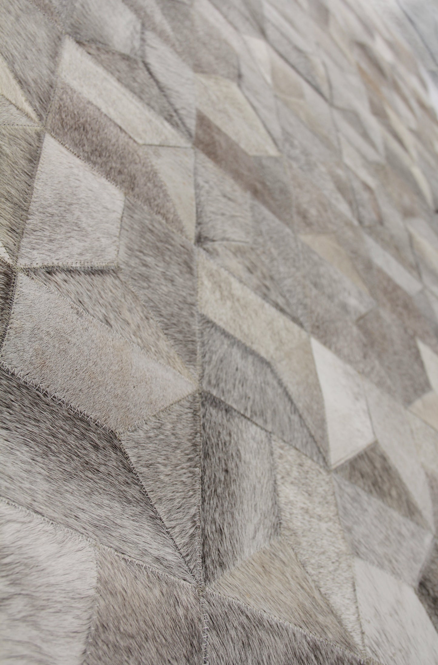 Close-up of a natural hide rug texture with overlapping diamond shapes in gray-beige tones.