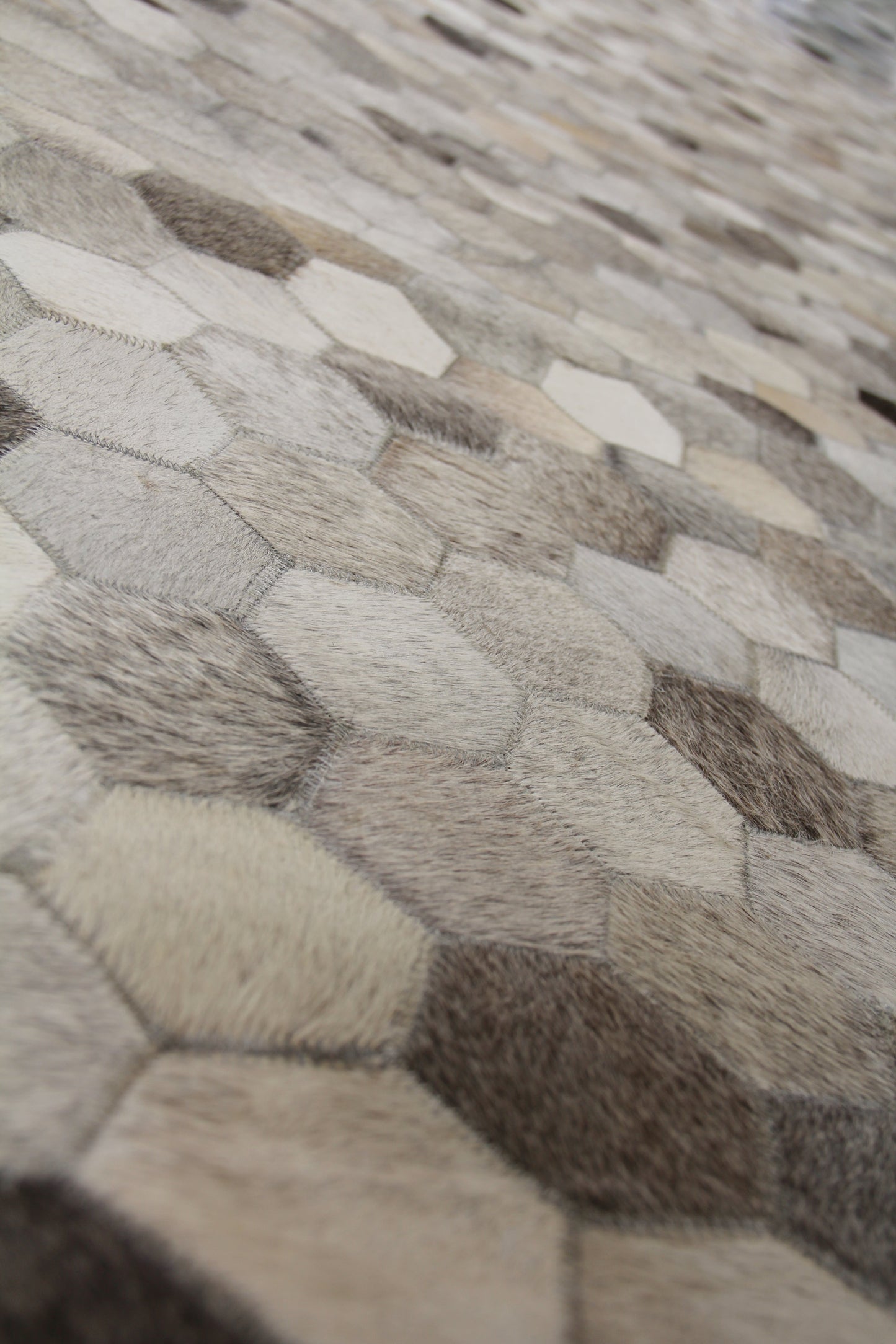 Natural hide indoor hand-stitched rug; neutral cream, beige, taupe, gray and brown tones for modern living spaces.