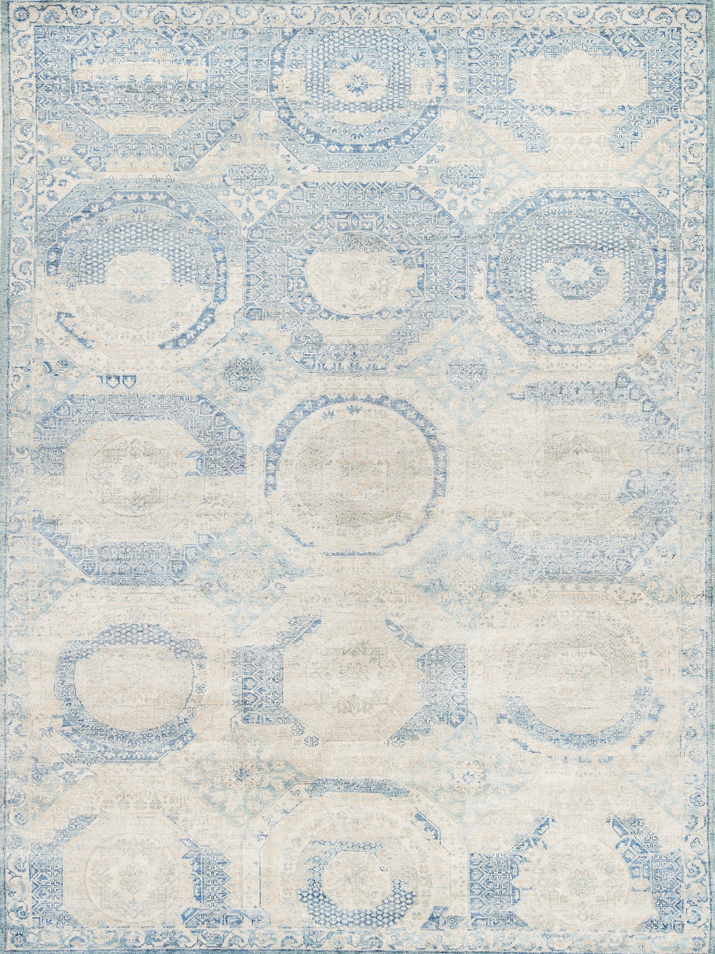 Light blue and cream vintage-style area rug featuring intricate patterns in various geometric shapes and floral details.