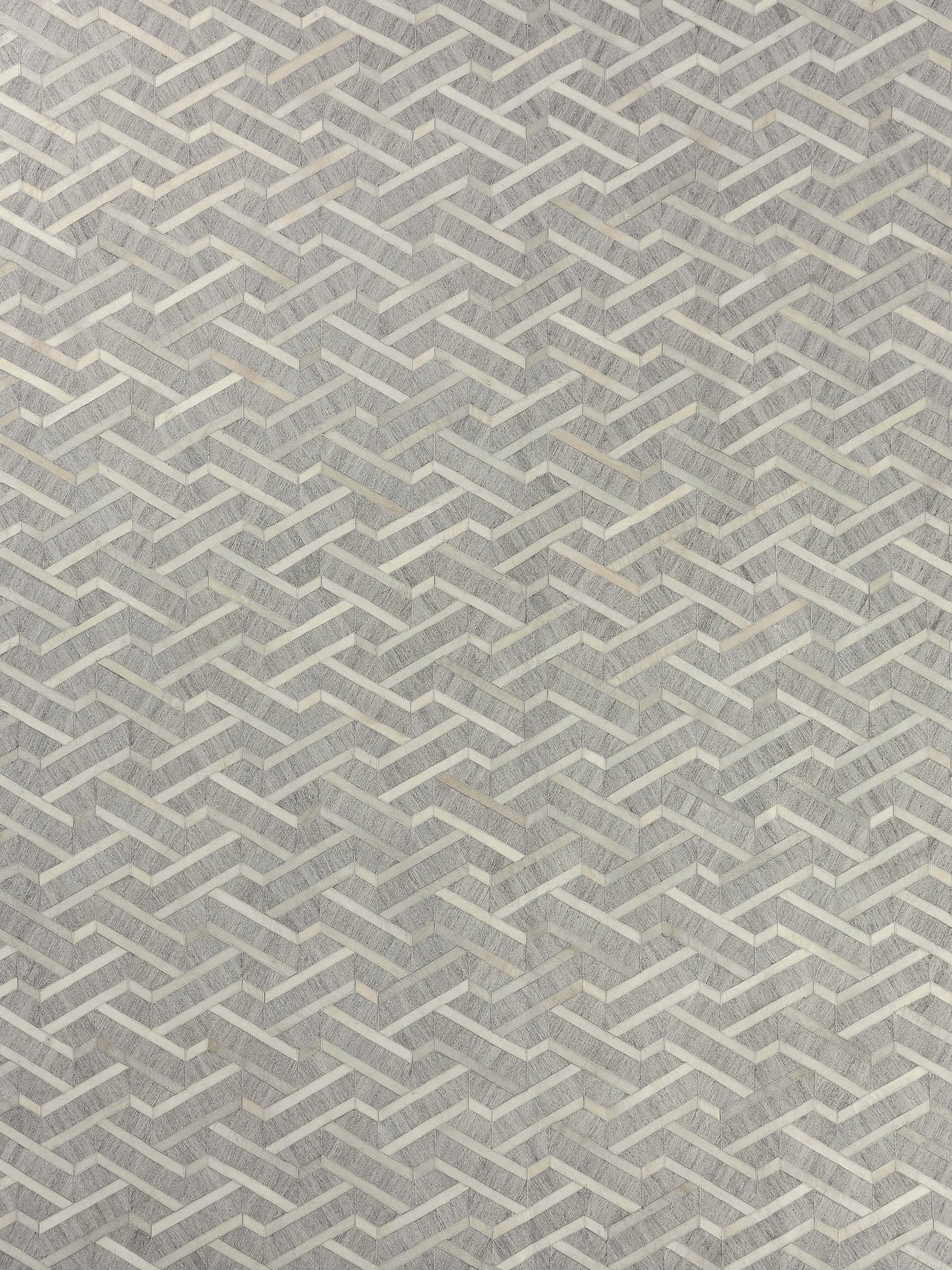 Woven rectangular rug with a light gray and natural-toned zigzag pattern.