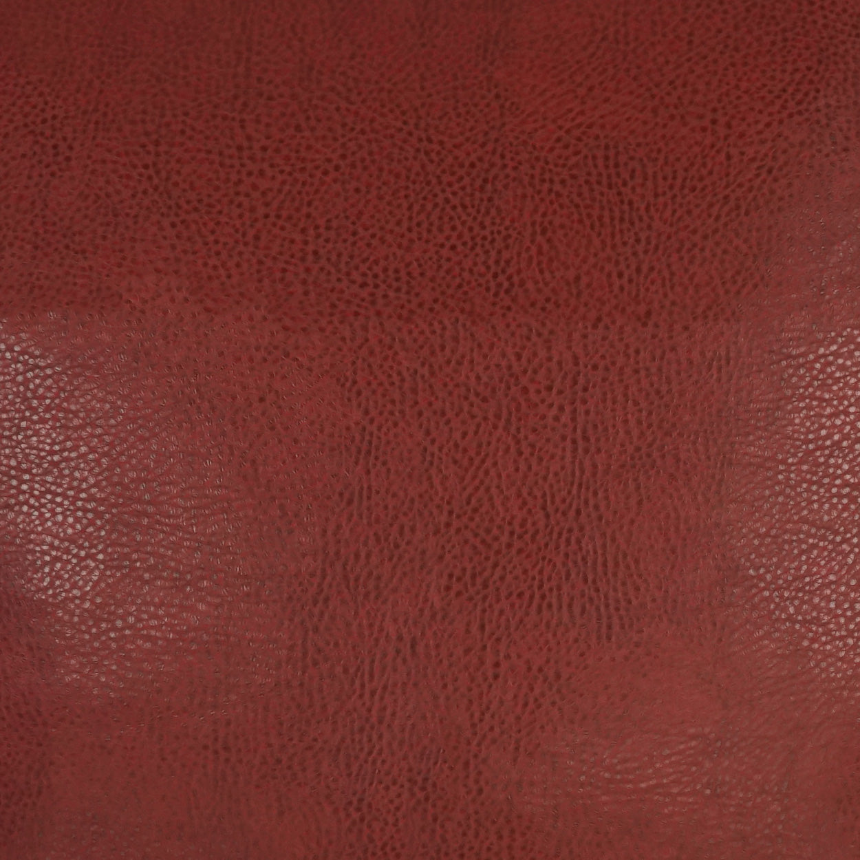 Close-up of red pebbled leather texture with grainy surface and warm burgundy color.