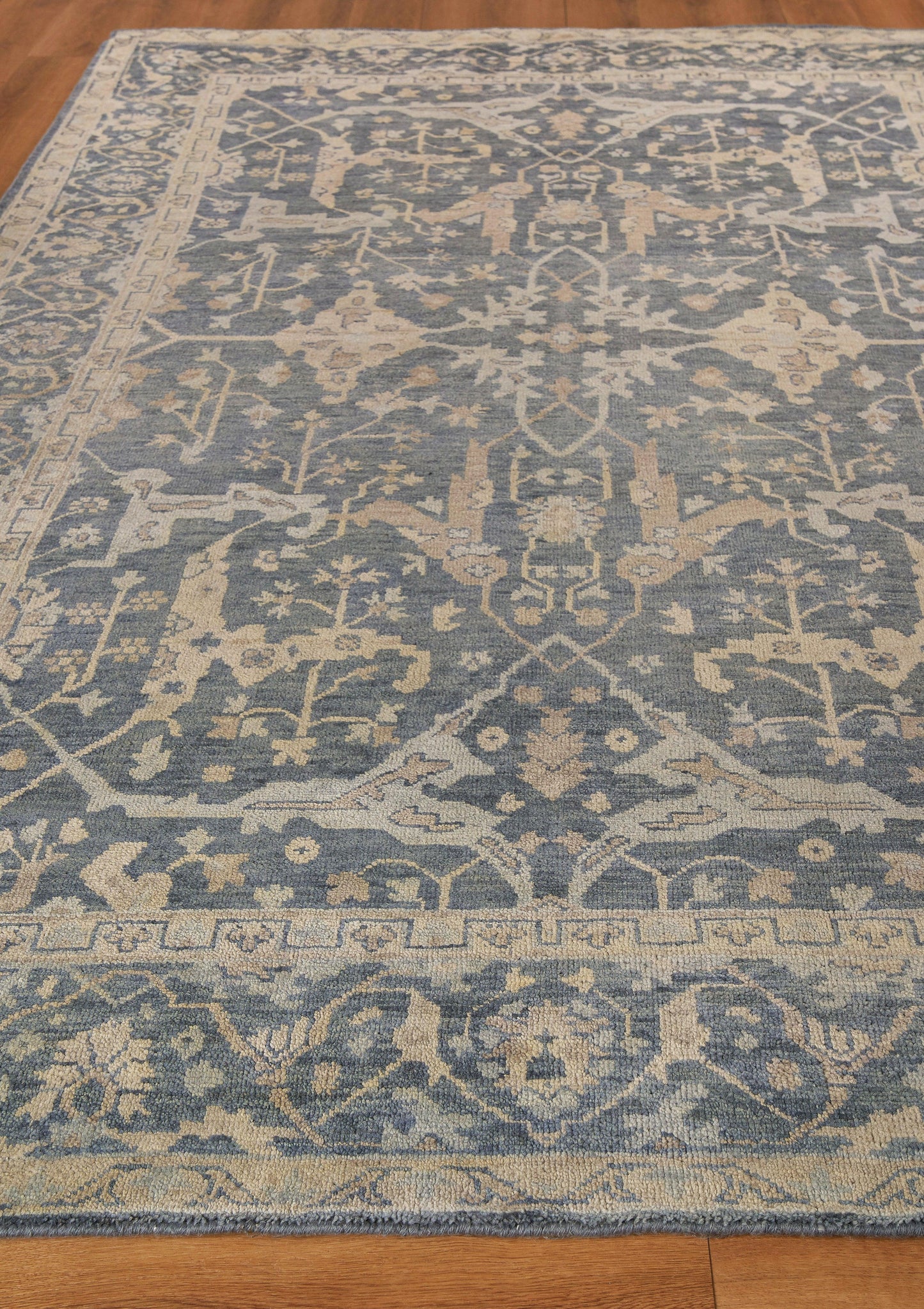 Rectangular blue and ivory oriental area rug with medallion-like motifs, floral vines and ornate border.