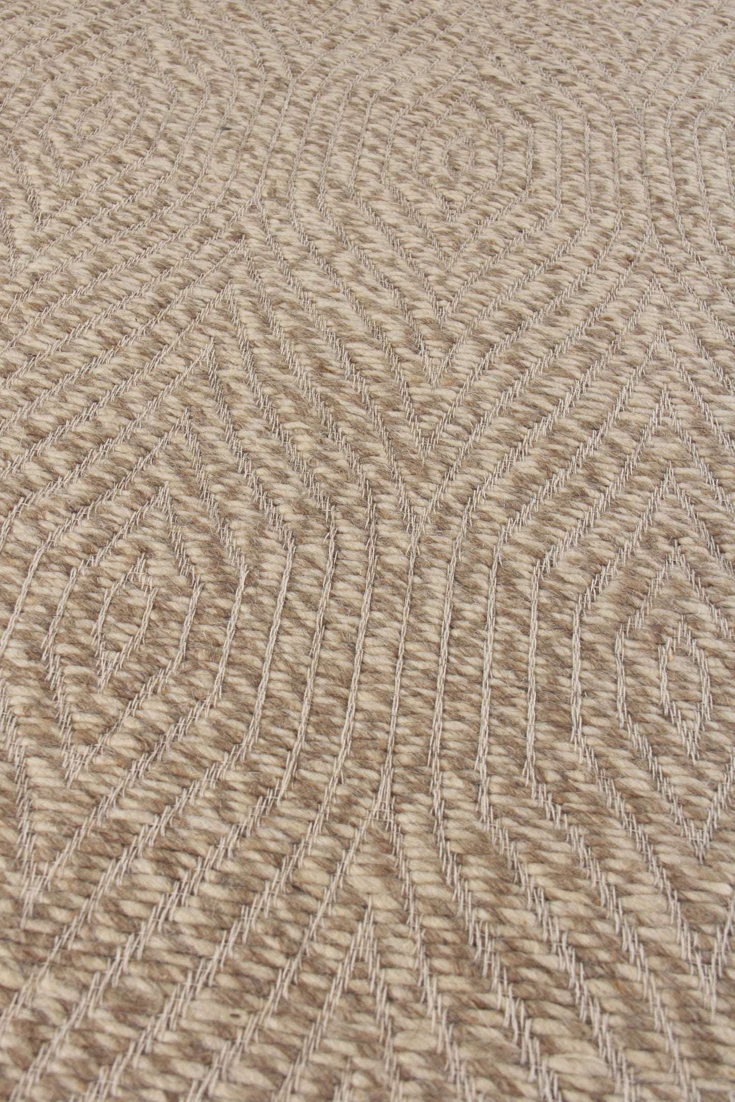 Natural beige jute rug close-up, rope-like braided lines create a curved geometric pattern.