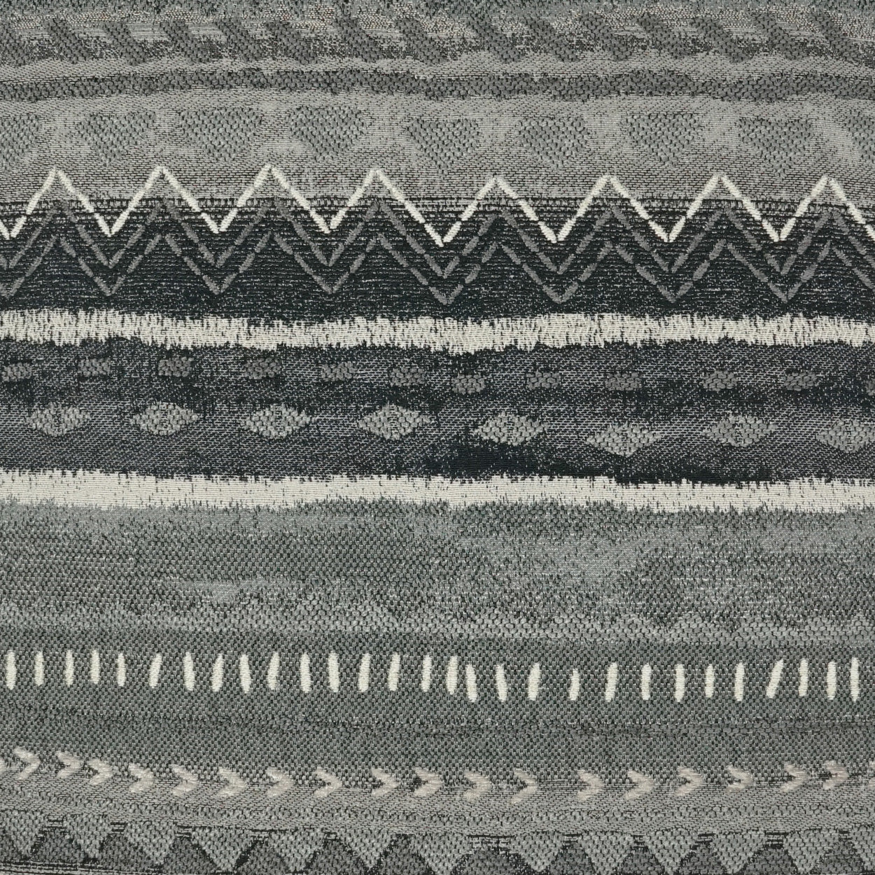 Gray woven fabric with horizontal geometric patterns: zigzags, stripes, & small diamonds.