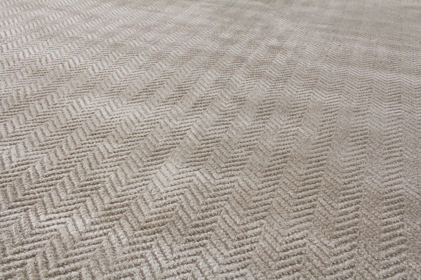 Beige herringbone rug with woven texture and subtle pattern.