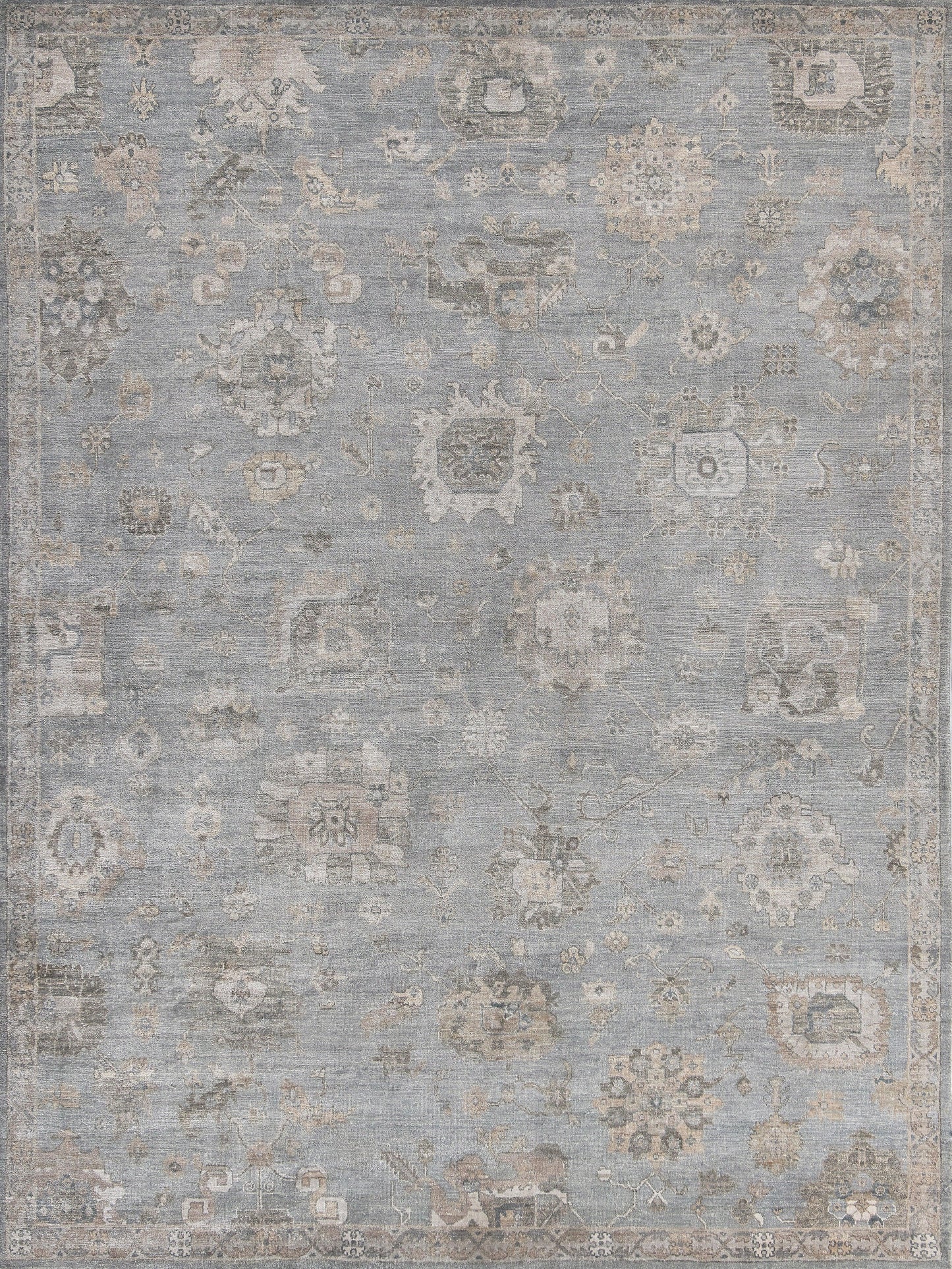 Blue-gray oriental rug with distressed beige floral medallions and ornate border; vintage-style floor covering.