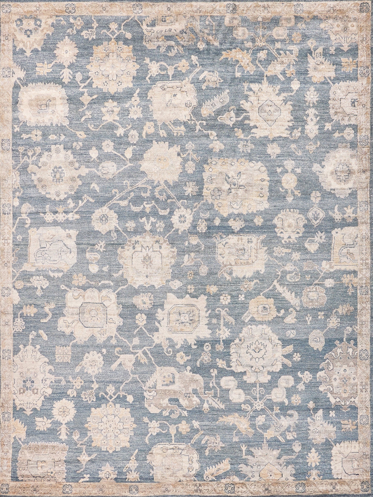 Blue, cream-toned distressed oriental area rug with floral motifs and ornate border.