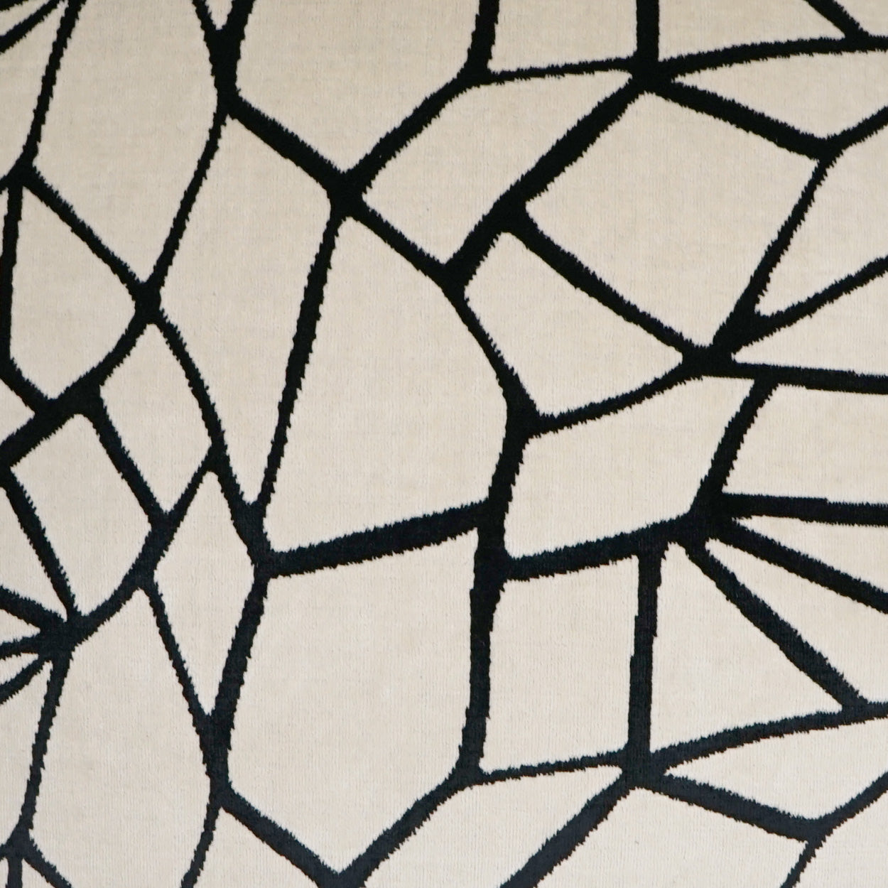 Beige fabric with bold black irregular mosaic crackle lines, upholstery or rug textile.