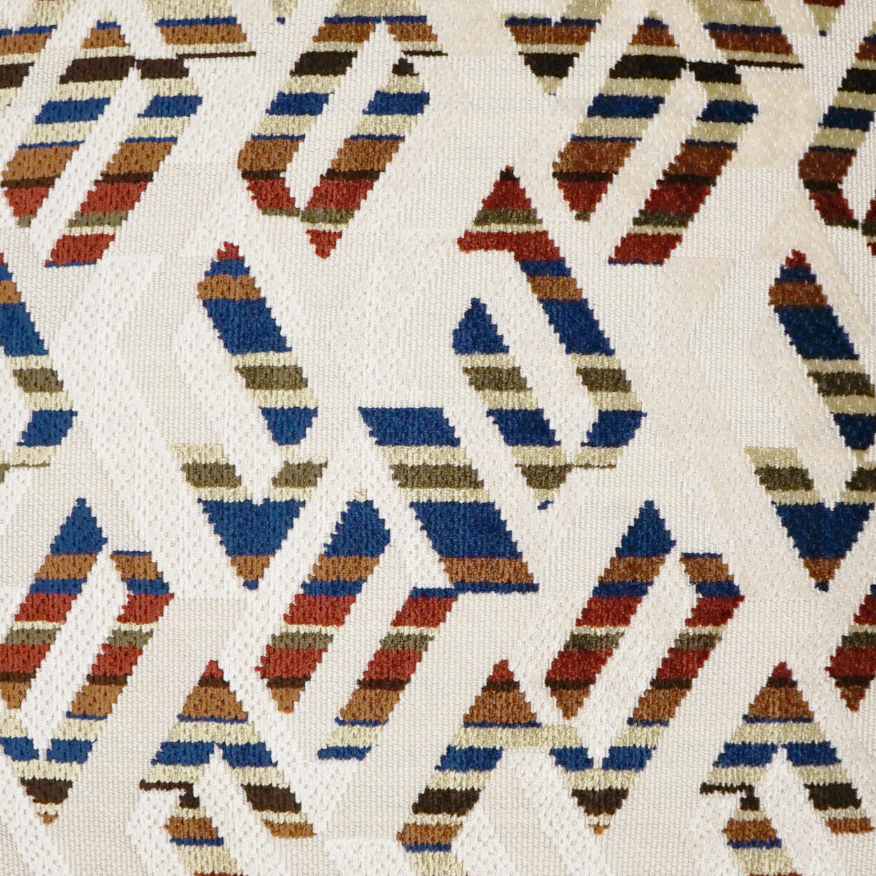 Pillow featuring woven fabric with geometric chevron triangles on a cream background and multicolor stripes in blue, red, brown & olive; 24" x 24