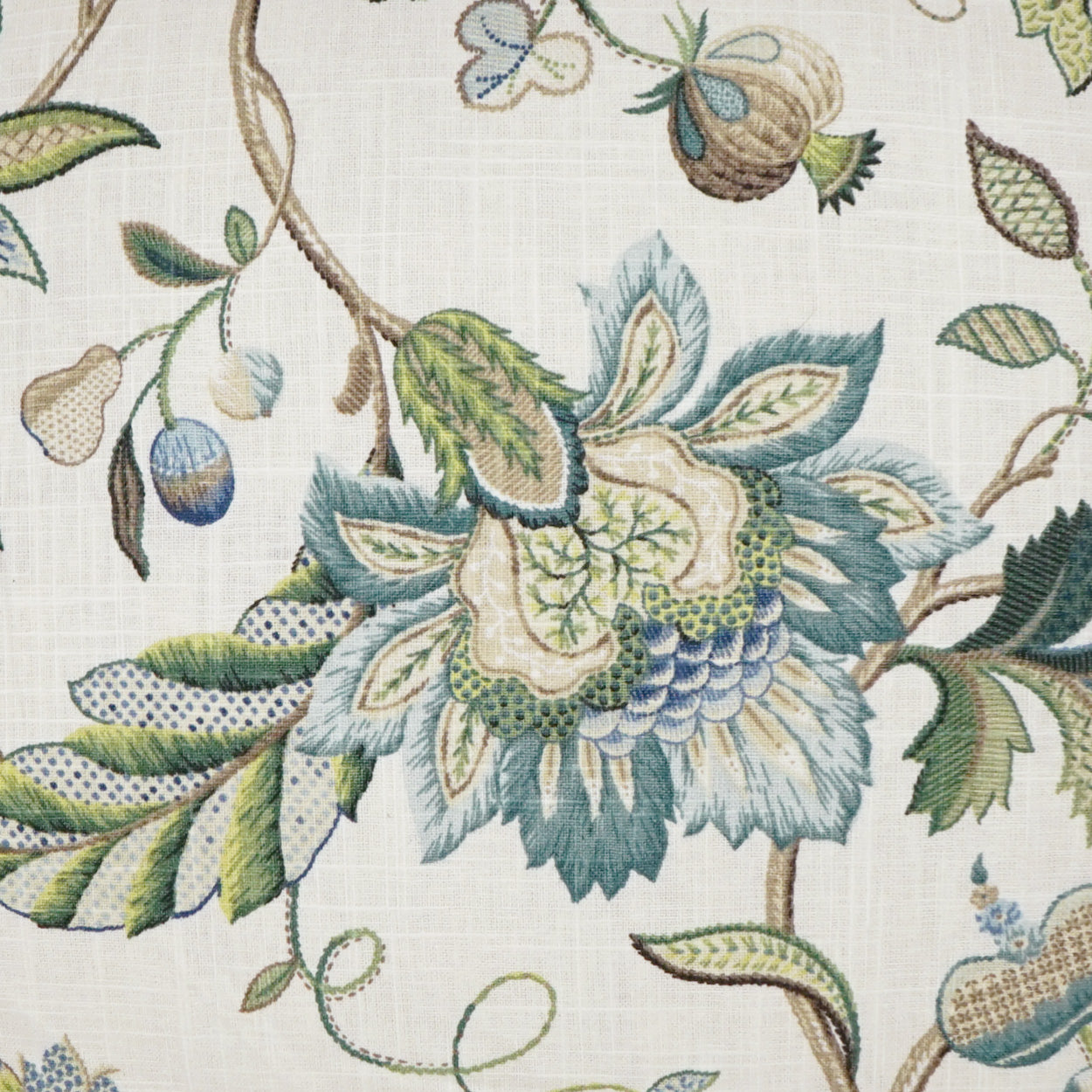 Floral fabric pattern with large blue-green flower and green leaves on a cream woven background.