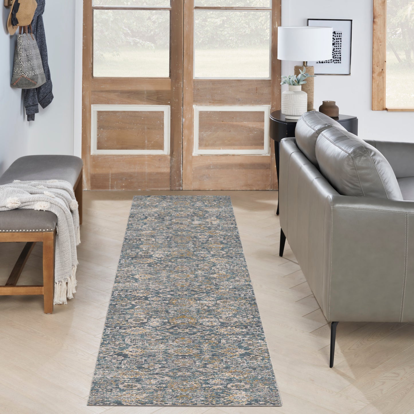 Blue-gray patterned runner rug with beige accents in a cozy living room hallway, flanked by a gray sofa and wooden doors.