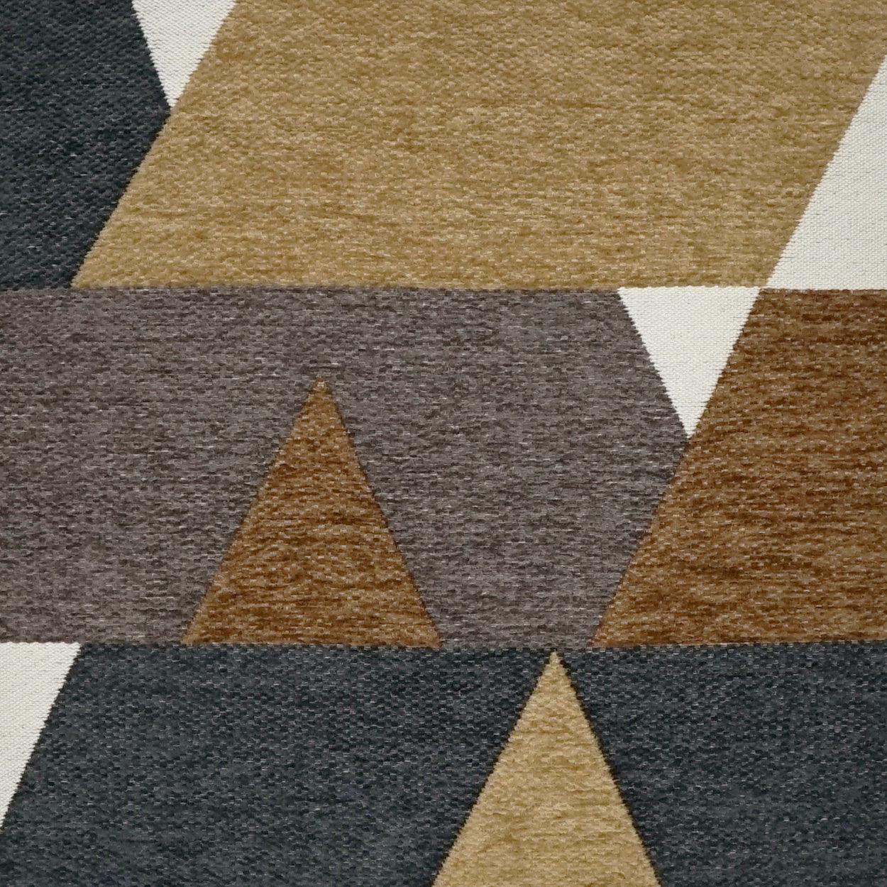 Textured geometric rug with overlapping triangular blocks in navy, charcoal, tan, beige and brown.