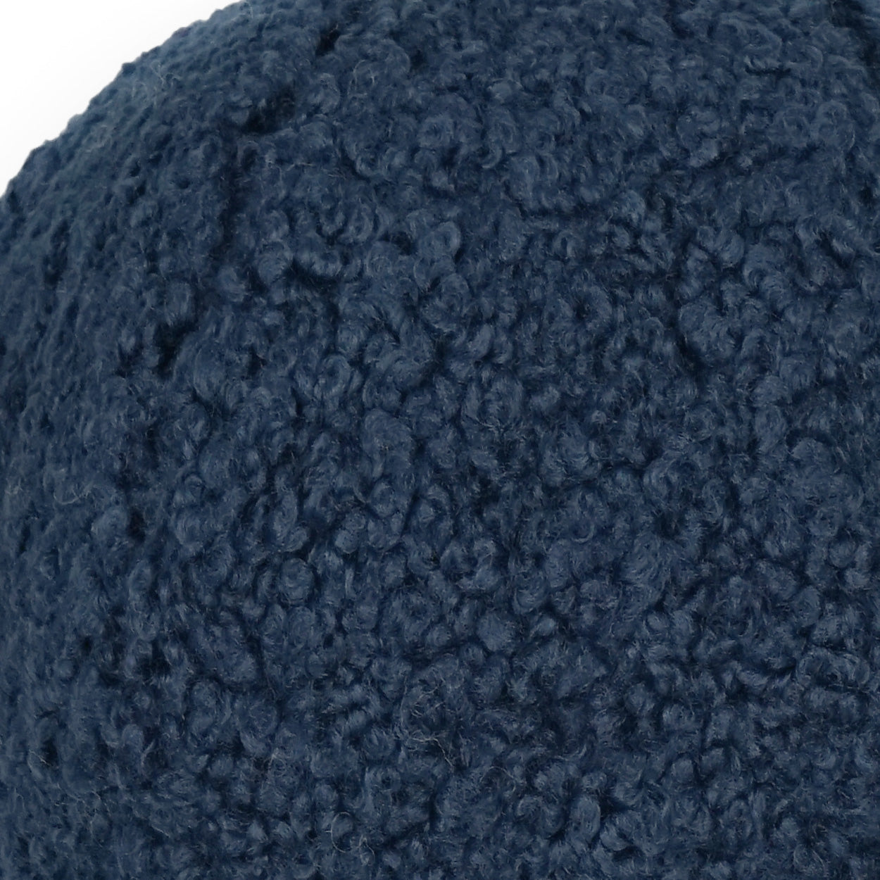 Close-up of dark navy faux fur (poodle-ball) texture on a navy solid pillow.