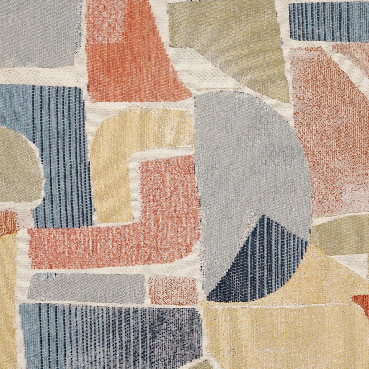 Colorful geometric patchwork fabric with blue, yellow, beige and coral tones; textured quilt-like rug.