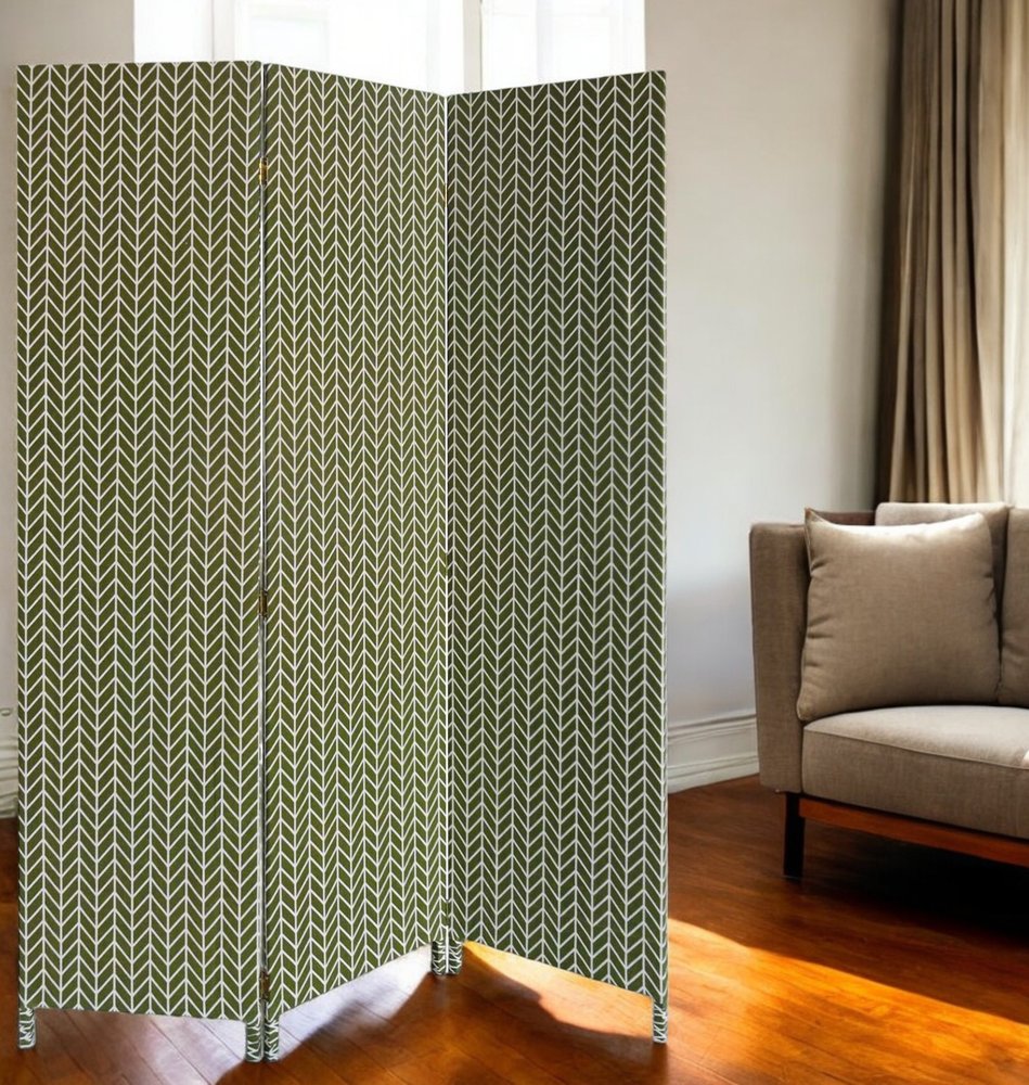 Three-panel folding room divider in green chevron leaf pattern with slim feet placed in a living room.