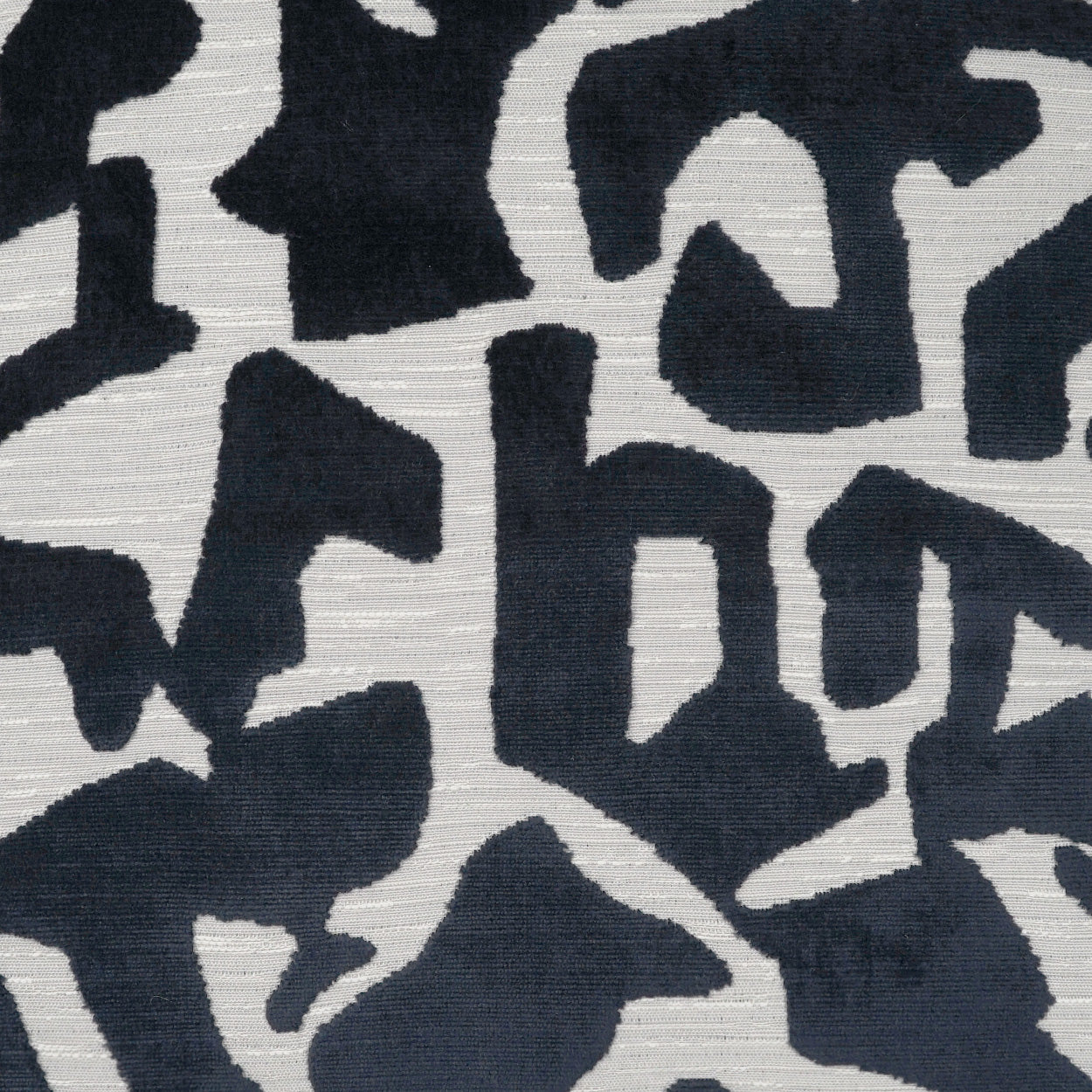 Abstract navy and off-white woven fabric with irregular black shapes; bold camo-like pattern for upholstery or apparel.