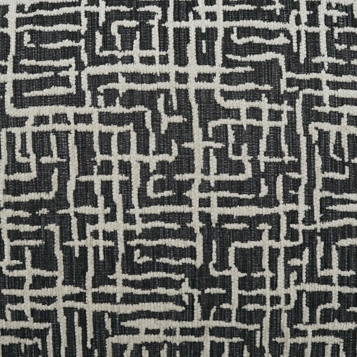 Woven black and white maze-pattern fabric with irregular white lines forming a geometric grid.