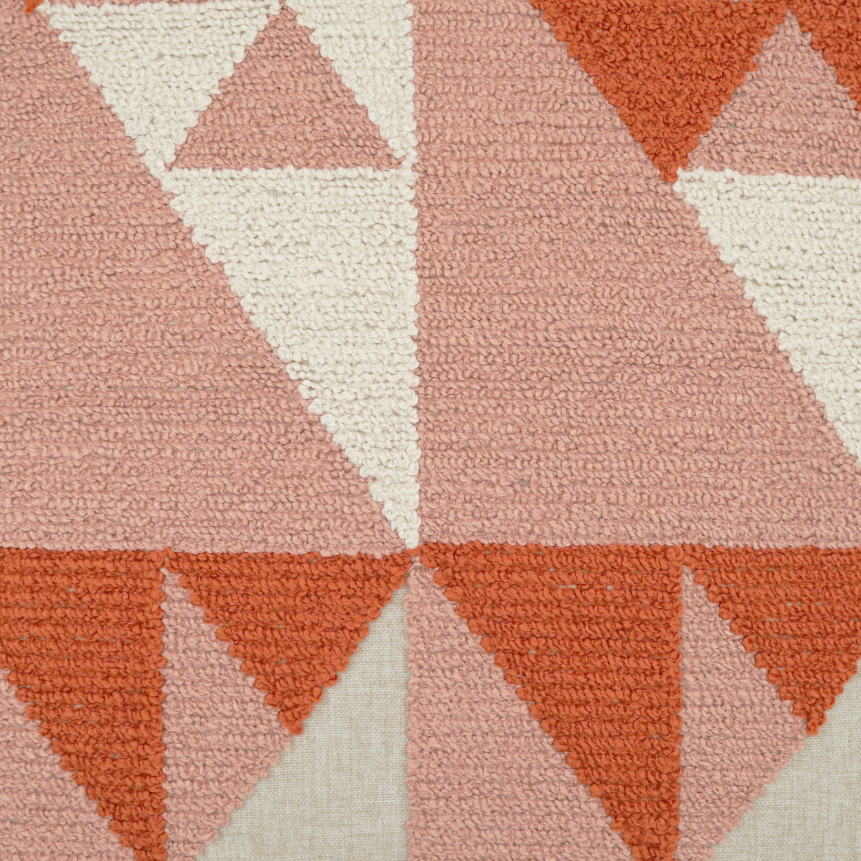 Geometric triangle pattern in pink, peach, cream and rust on a textured woven fabric.