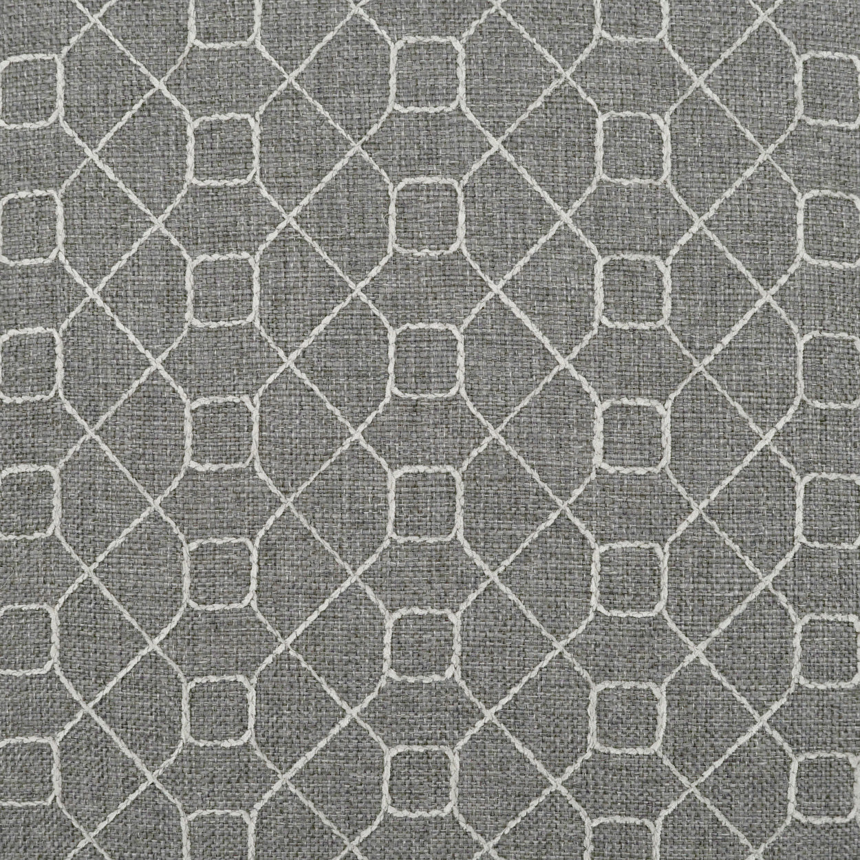 Grey pillow with textured fabric and a white geometric lattice pattern of interlocking diamonds & square nodes.