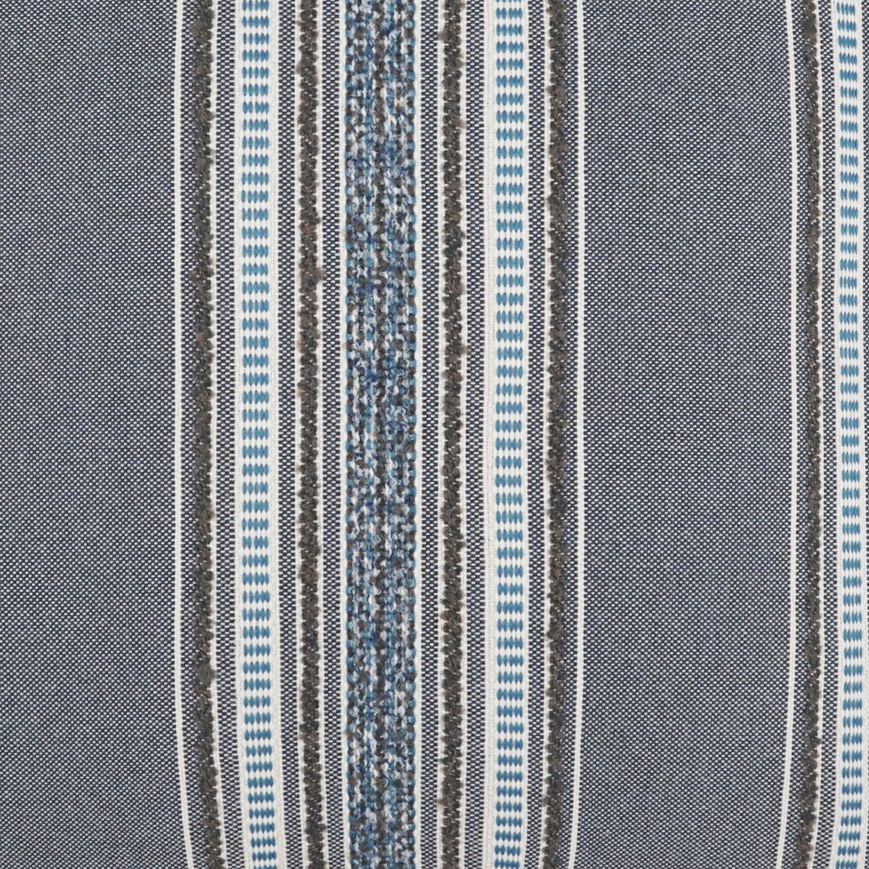 Pillow covered in woven fabric with vertical indigo, gray, white and black stripes; textured weave and varied stripe widths.