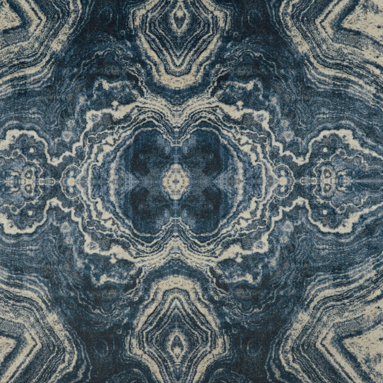 Indigo blue and beige fabric rug with a symmetrical kaleidoscopic medallion motif and swirling layers.