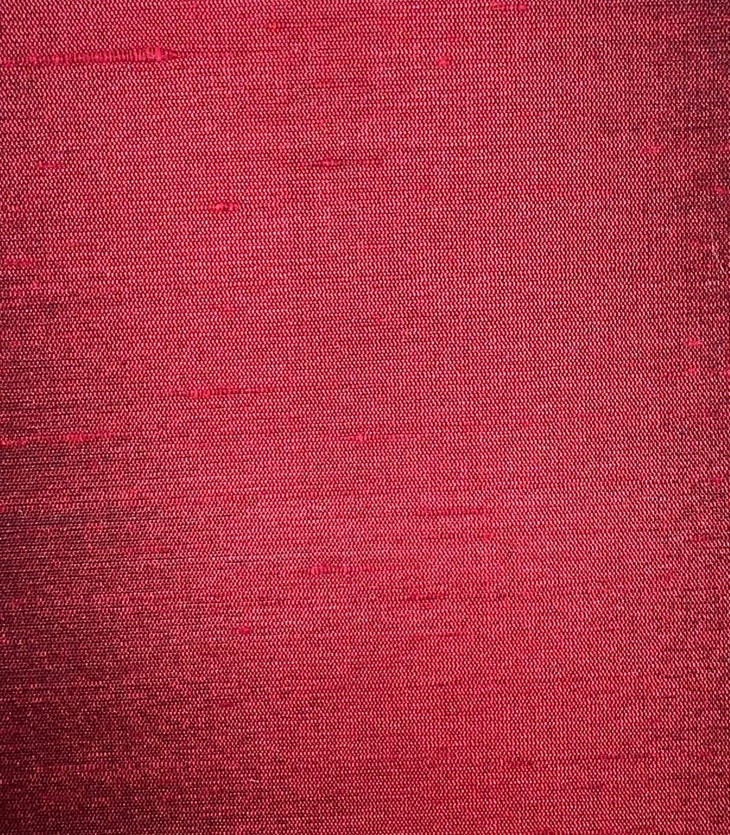 Close-up of crimson red woven fabric texture with visible fibers and subtle weave.