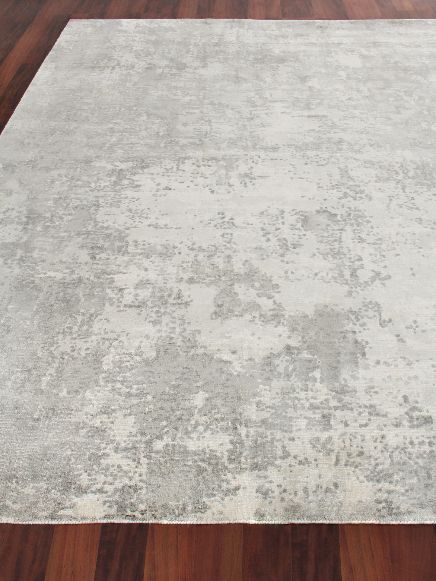 Rectangular light gray and cream indoor hand loomed area rug, 4' x 6', with an abstract washed pattern on a dark wood floor.