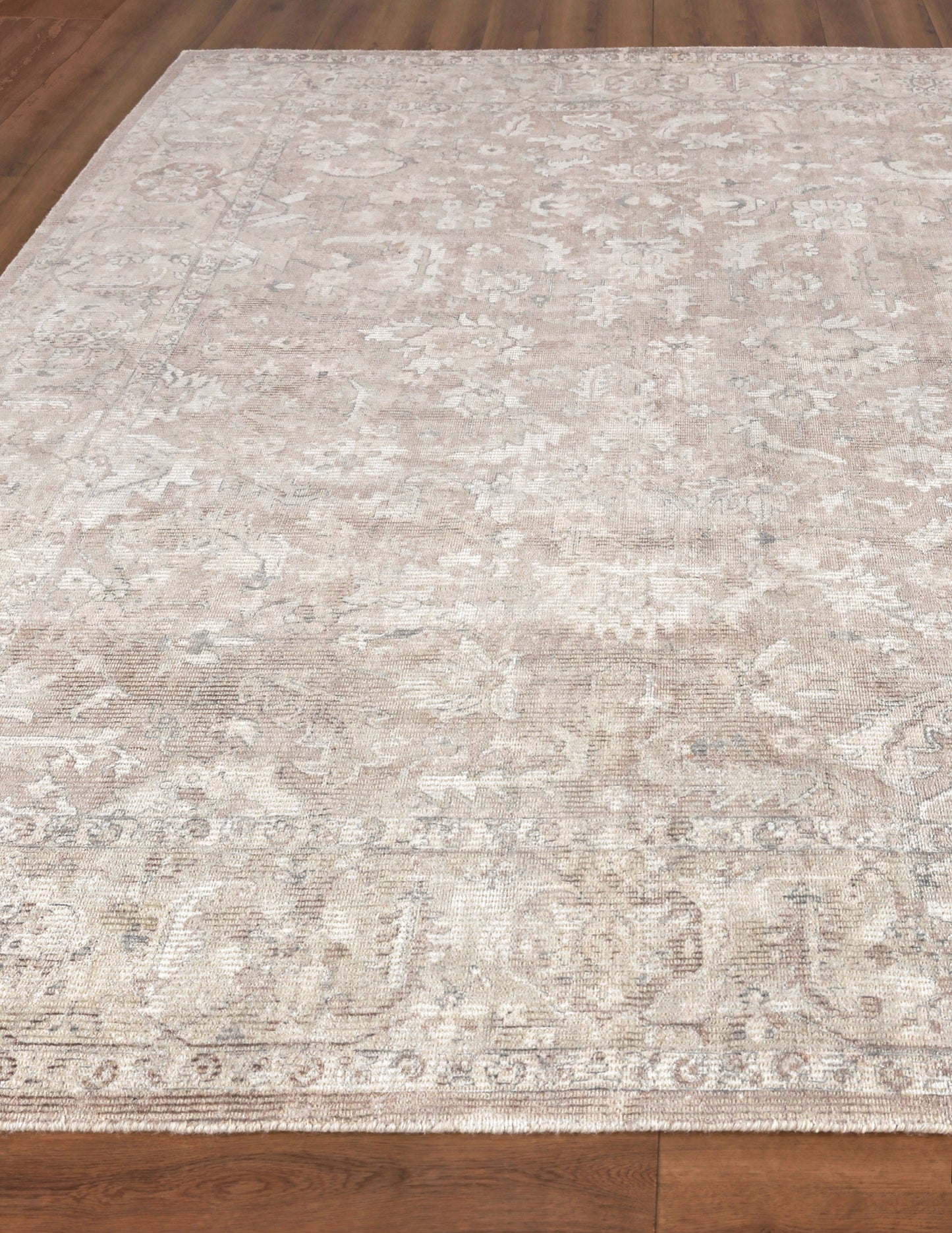 Rectangular beige and ivory distressed patterned area rug with subtle floral motifs, low-pile, on wood floor.