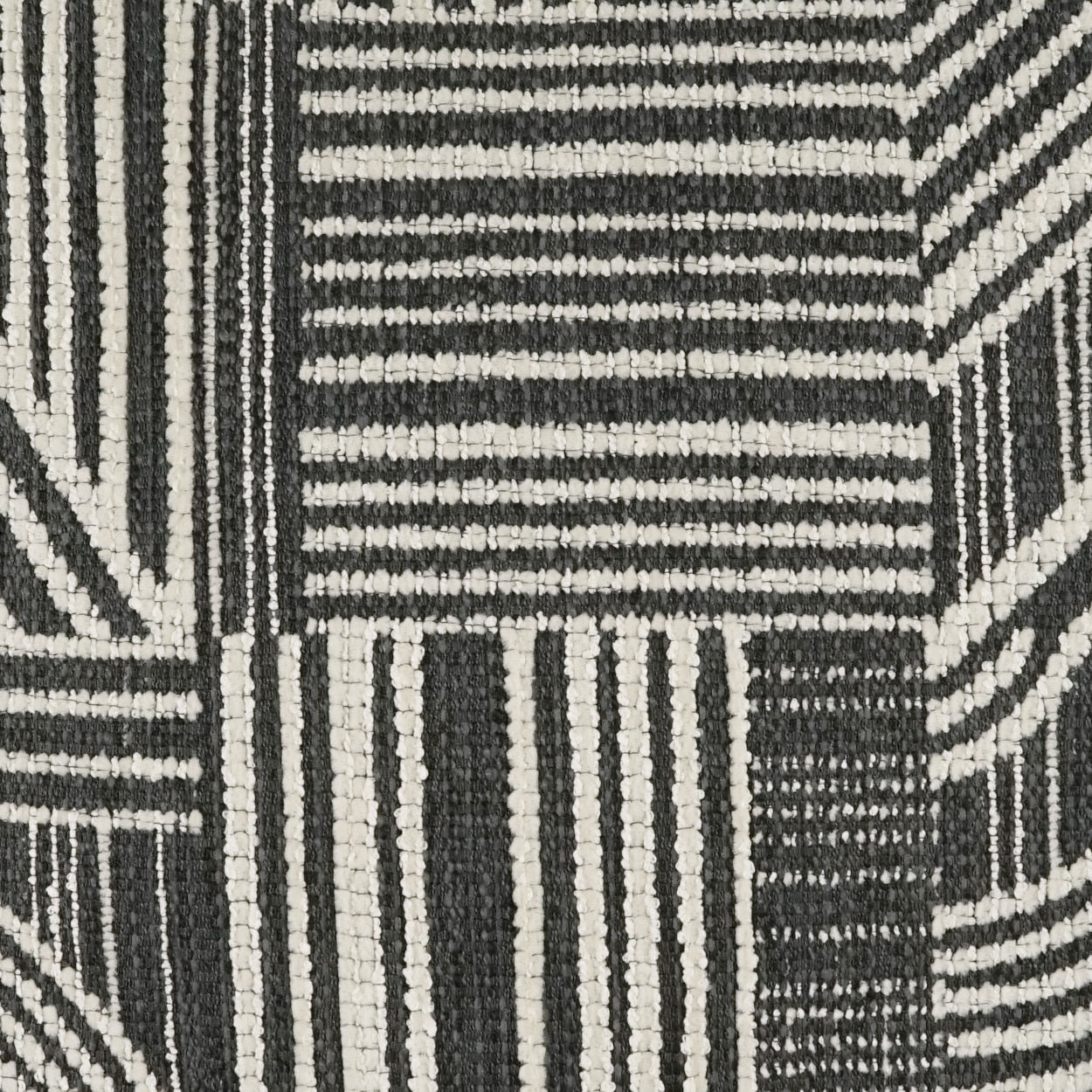 Black and white geometric woven rug texture with patchwork stripes and blocks.